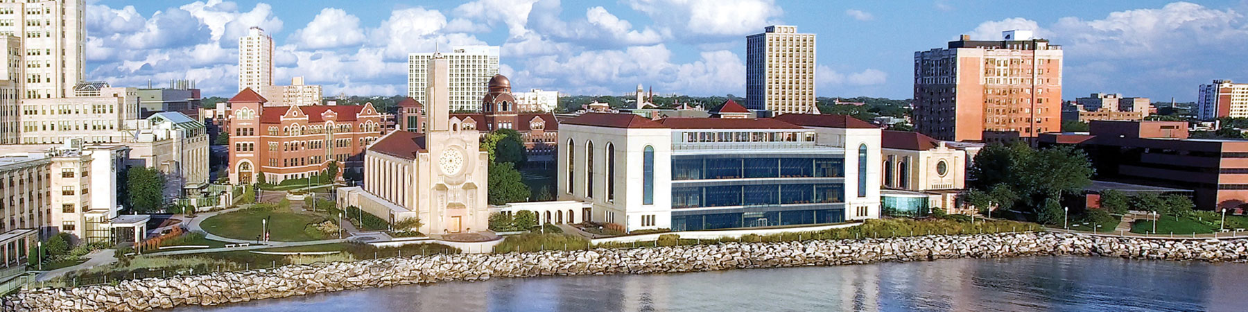 An aerial view of the Lake Shore Campus from lakeside with beautiful cumulus clouds in the sky. An aerial view of the Lake Shore Campus from lakeside with beautiful cumulus clouds in the sky.