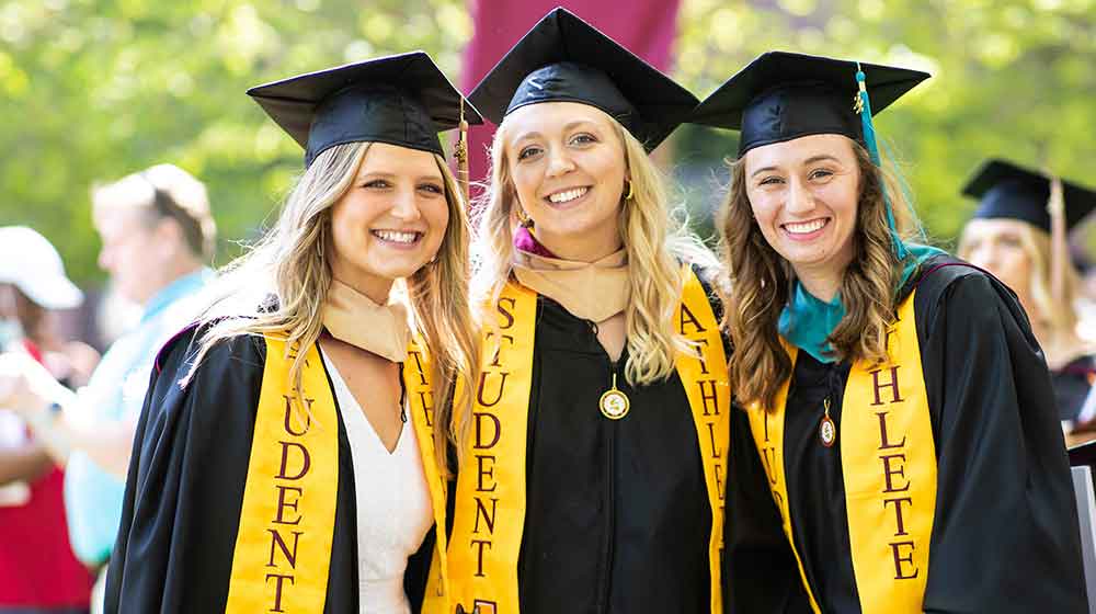 Three students in graduation gowns Three students in graduation gowns